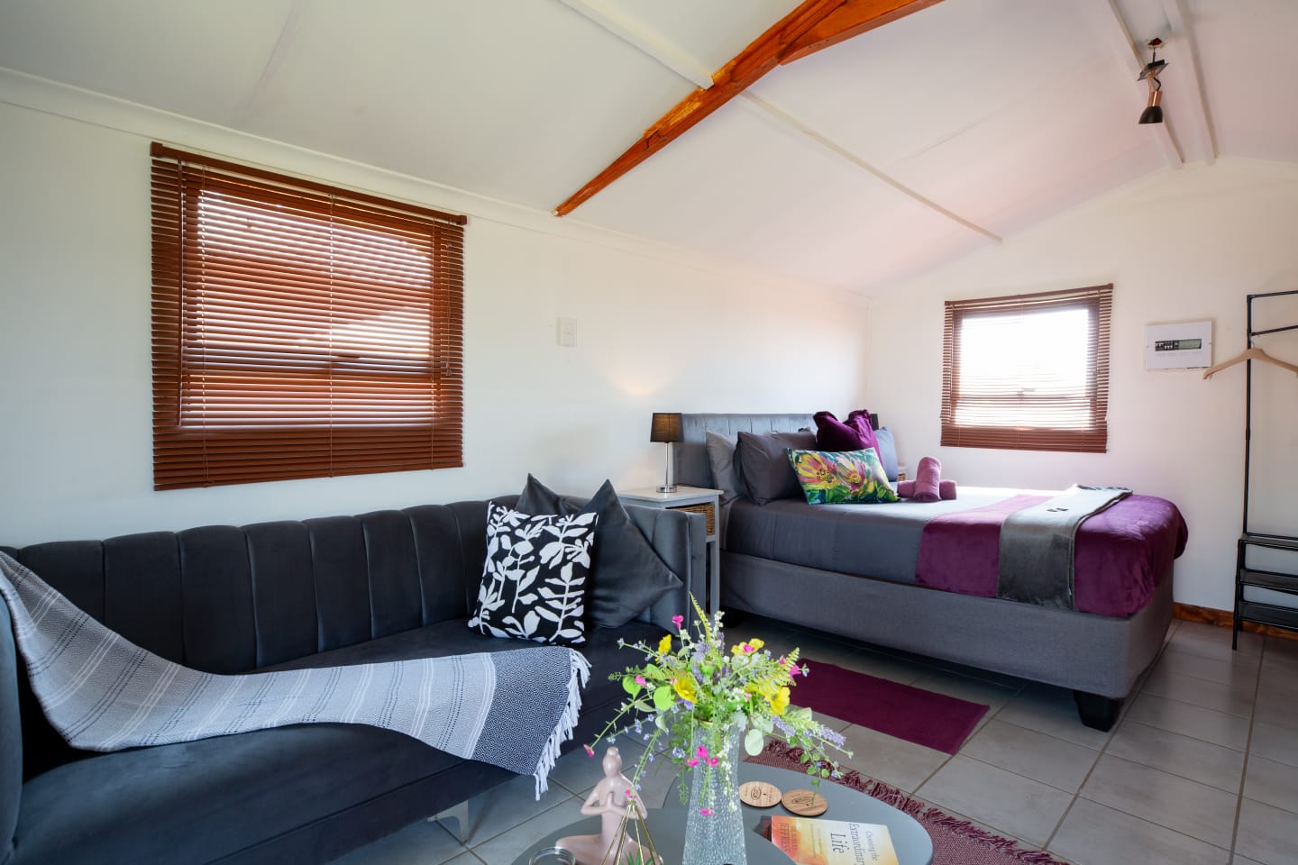A warm and spacious cabin interior with a comfortable lounge area, soft bedding, wooden finishes, and a relaxed farm-stay feel.